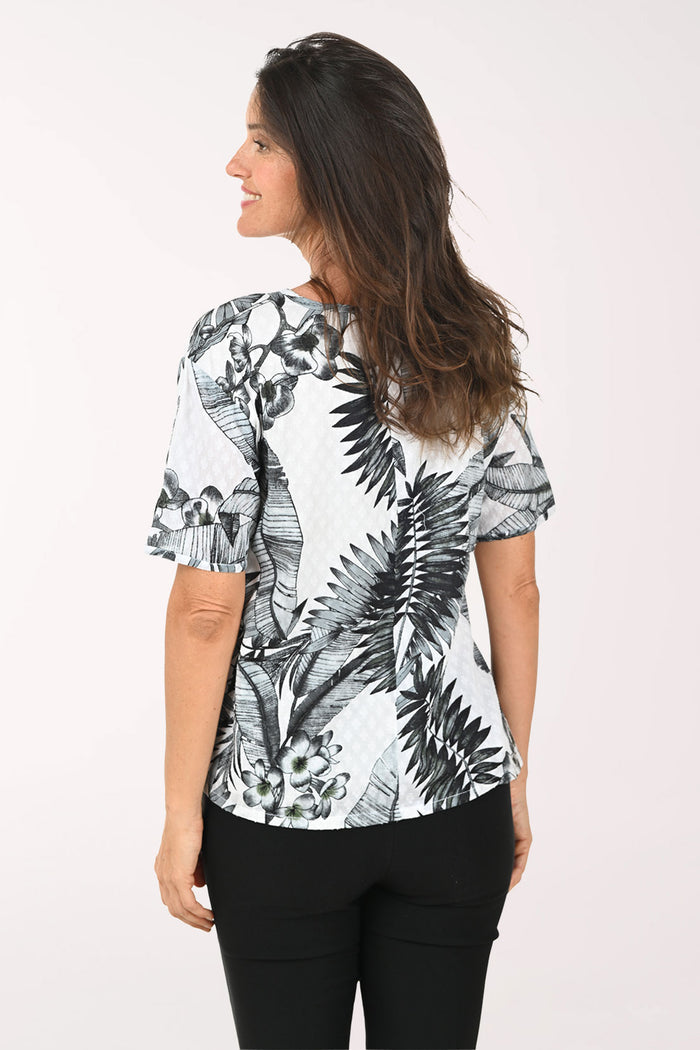 Woman wearing a black and white floral print top on a white background