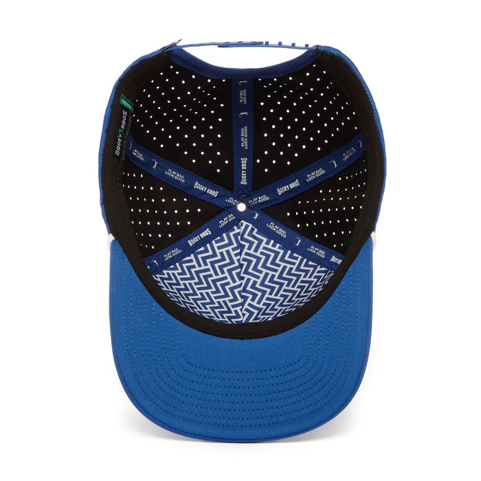 The image shows the inside view of the Fore! - Performance Golf Rope Hat - Snapback. It features performance material, a black inner lining with white dots, crisscrossing blue bands, and a blue and white zigzag pattern under the bill.