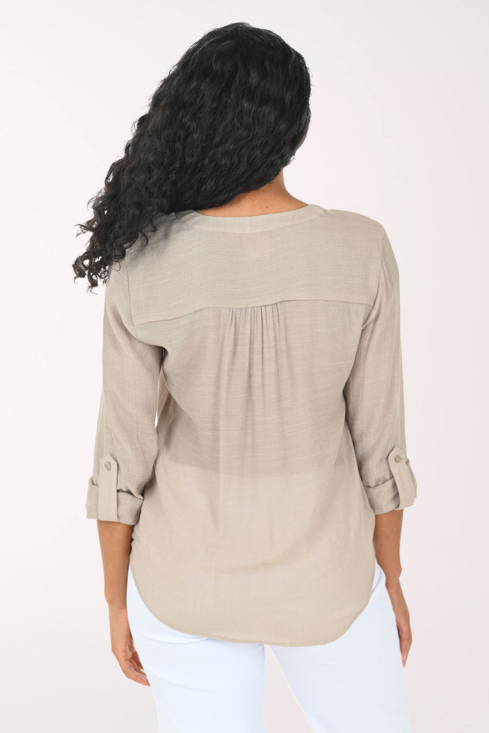 Woman wearing a beige button-up shirt with a white background
