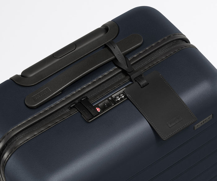The Bigger Carry-On suitcase in Navy Blue shown shown from above highlighting TSA-approved combination lock and recycled leather luggage tag
//
All of our suitcases come with a leather luggage tag. Add up to three letters to personalize yours and stand out at the baggage claim.