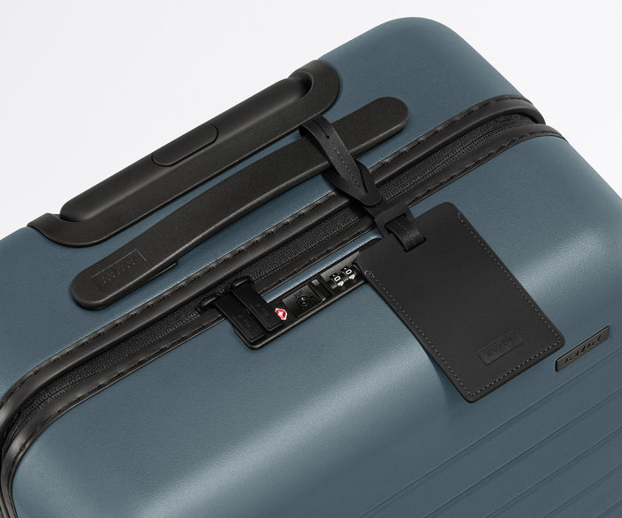 The Carry-On suitcase in Coast Blue shown shown from above highlighting TSA-approved combination lock and recycled leather luggage tag
//
All of our suitcases come with a leather luggage tag. Add up to three letters to personalize yours and stand out at the baggage claim.