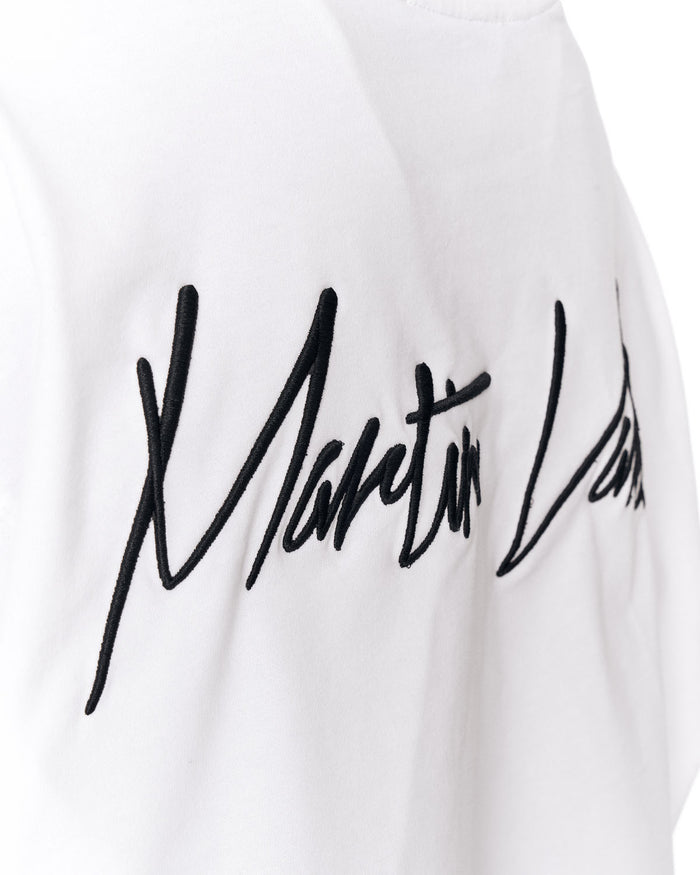 Close-up of a white garment with a large black cursive script logo across the chest.