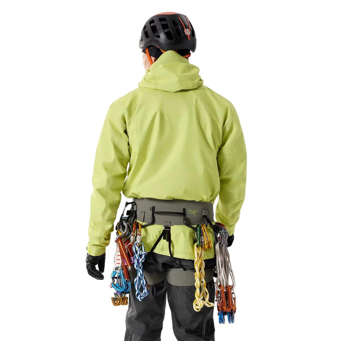 Person wearing a green jacket and black helmet with Arcteryx AR-395a climbing harness in back view