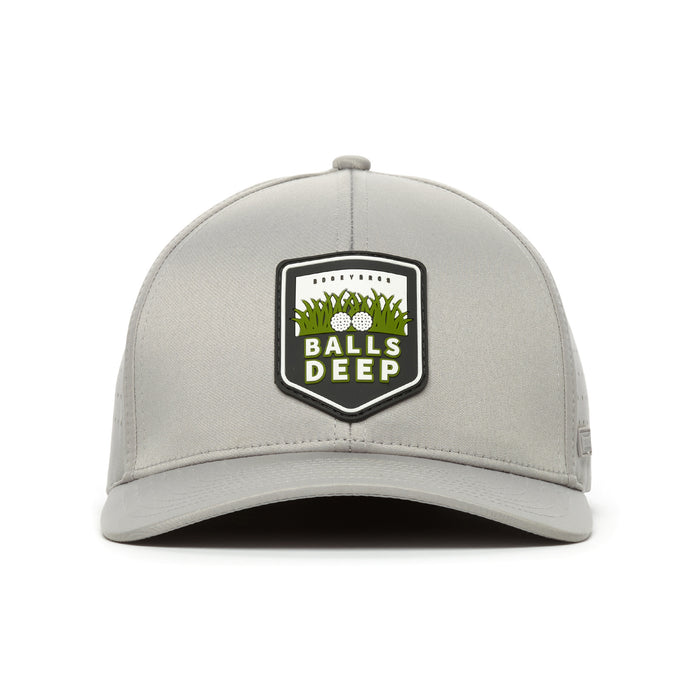 The Bogey Bros Balls Deep - Performance Golf Hat - Stretch Fit is a light gray cap with a black and white patch showing two golf balls on green grass and “BALLS DEEP” in bold. Made of performance material, shown front view on plain white.
