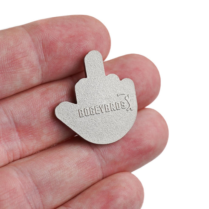 A hand holds the Birdie Finger - Ball Marker, a heavy metal token shaped like a raised middle finger. "BOGEYBROS" is engraved on the front, and it features durable iron nickel plating for long-lasting use.