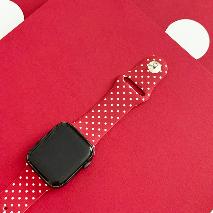 Burgundy Apple Watch strap with white polka dots, by Coconut Lane, shown against a red background with white spots.