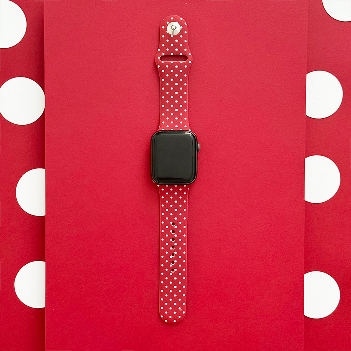 Burgundy Apple Watch strap with white polka dots, displayed on a red and white polka dot background.