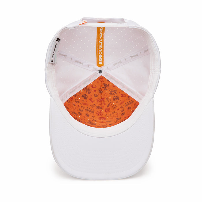 The image shows the inside of a white baseball cap. The inner crown is light pink with white dots, and the sweatband is orange with small playful doodles. The label inside reads SERIOUSLY FUN. The brim is plain white.