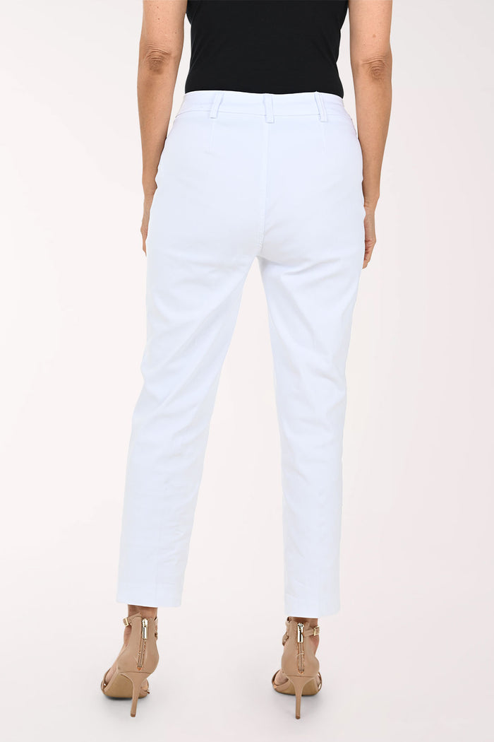 White cropped ankle-length pants with front patch pockets and decorative gold-tone buttons, shown on a model wearing a black top and tan heeled sandals against a light studio background.