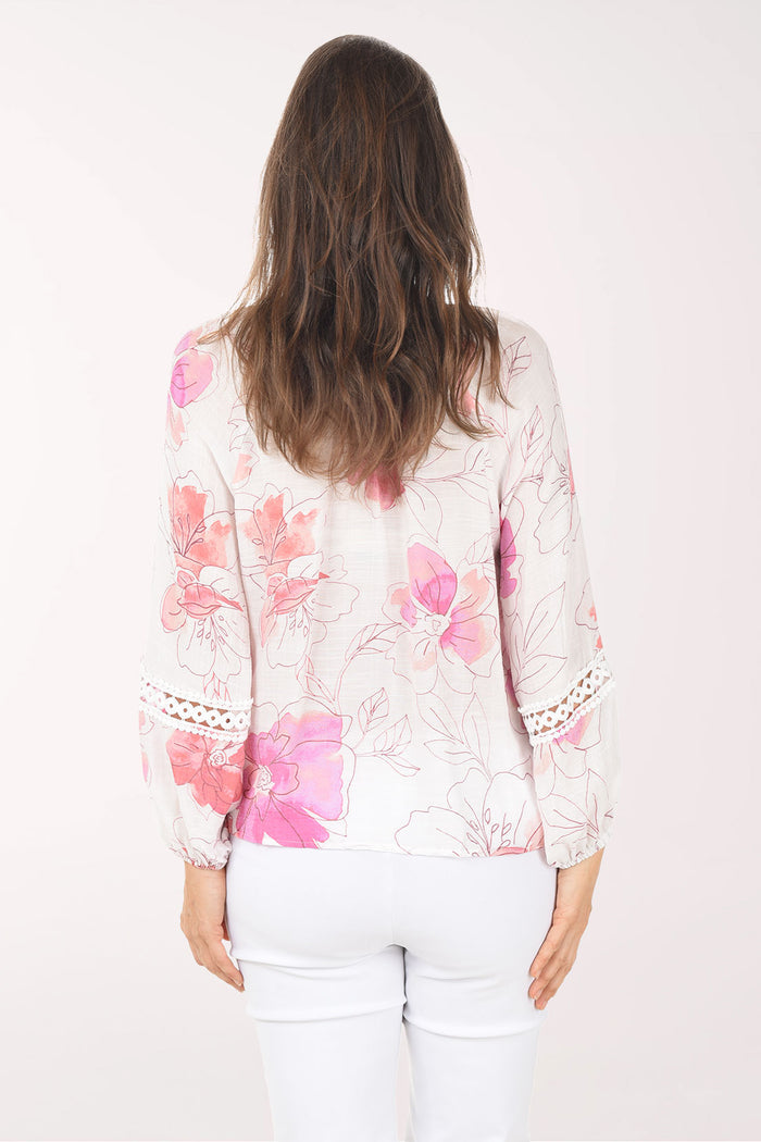 Woman wearing a white blouse with pink floral patterns on a white background