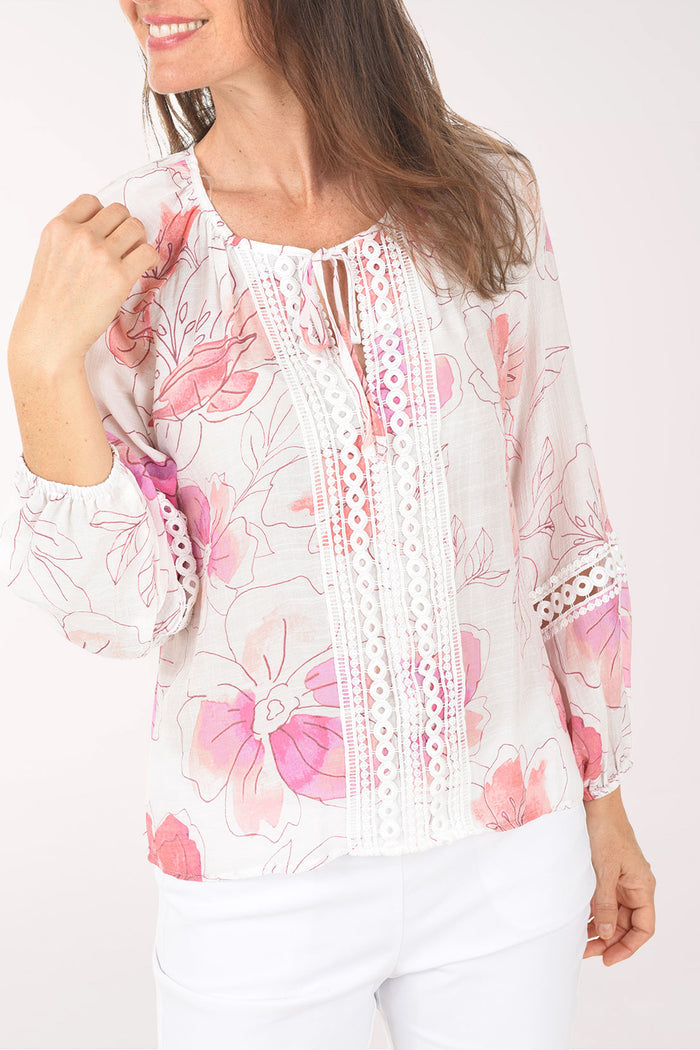 Woman wearing a white blouse with pink floral patterns on a white background