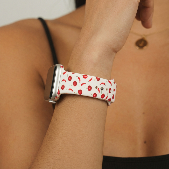 Coconut Lane Cherry Spice Apple Watch strap with a red cherry pattern worn on a wrist.