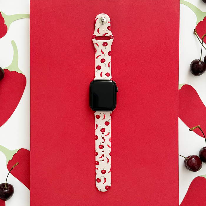 Cherry Spice Apple Watch strap with a cherry pattern, displayed on a red background decorated with cherries.