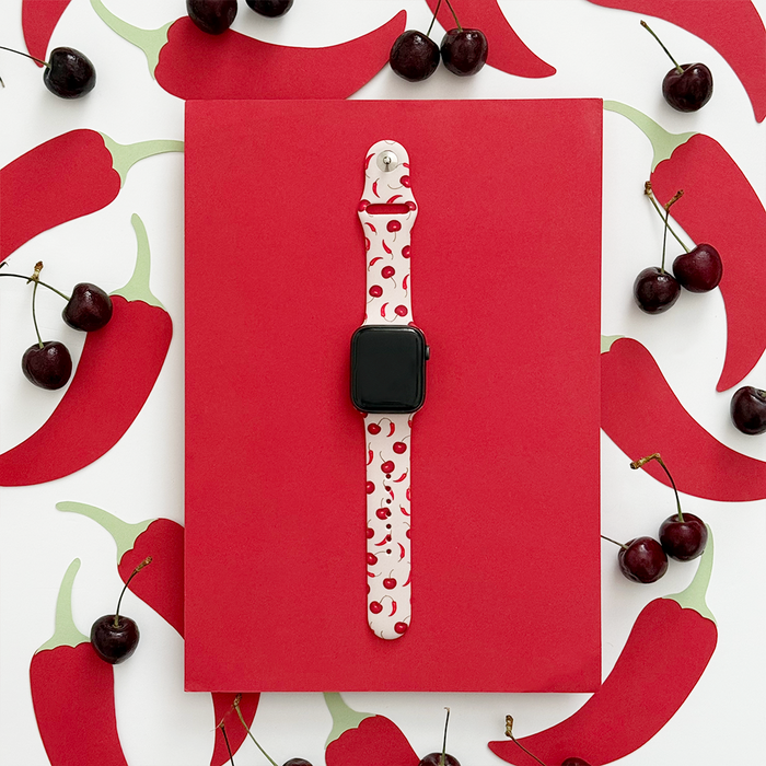 Cherry Spice Apple Watch strap with red chili pattern, shown on red paper with cherry and chili accents.