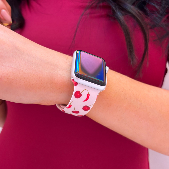 Cherry Spice Apple Watch strap by Coconut Lane, featuring a red and pink pattern, worn with a burgundy top.