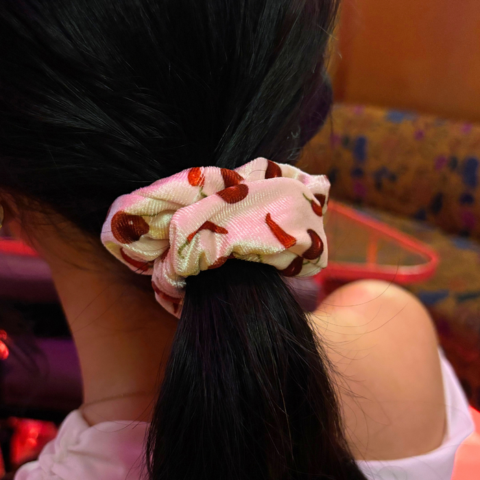 Ponytail secured with a red Cherry Spice scrunchie featuring bright red cherry print by Coconut Lane.