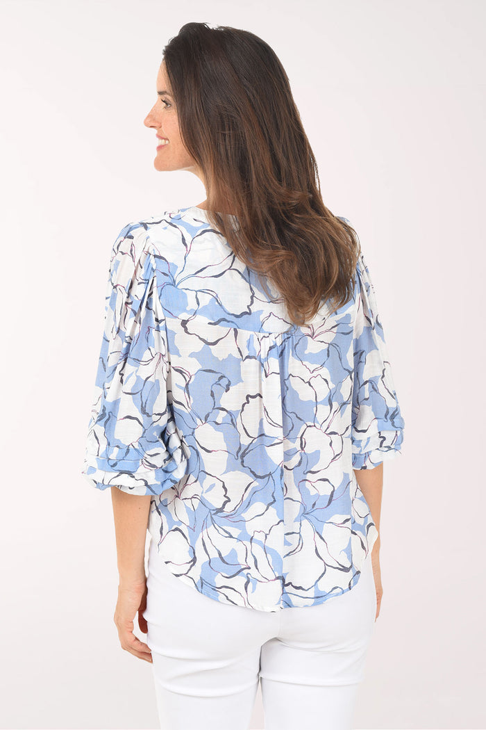 Woman wearing a blue floral blouse against a white background