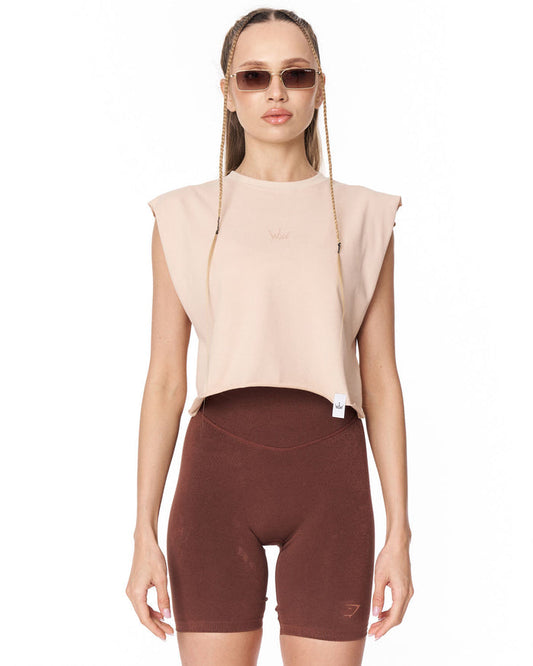 A model wearing a sleeveless beige crop top and dark brown fitted biker shorts against a plain white background.