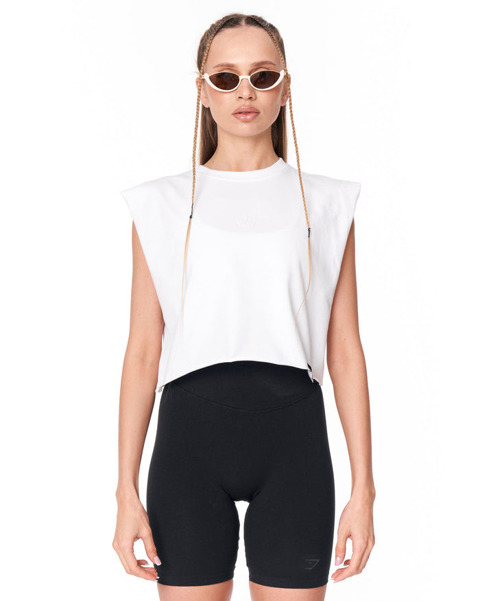 A model wearing a white sleeveless crop top with a sheer mesh chest panel and black bike shorts, styled with cat-eye sunglasses against a plain white background.