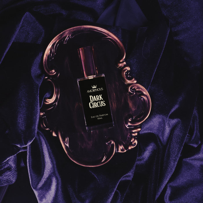 Perfume bottle labeled 'Dark Circus' on a dark purple fabric background