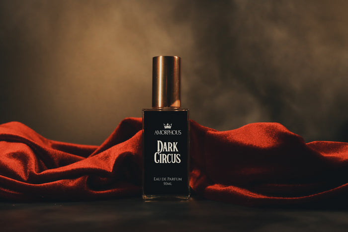 Perfume bottle labeled 'Dark Circus' on a red fabric with a dark background
