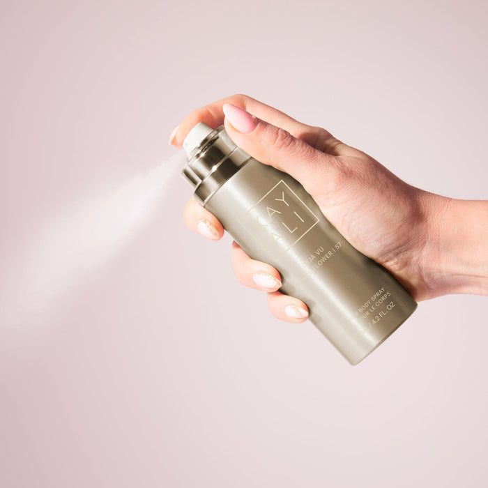Hand holding a metallic spray bottle with a light background