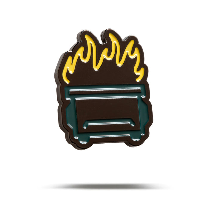 The Dumpster Fire - Ball Marker is a stylized enamel pin shaped like a green dumpster with yellow and orange flames, iron nickel plating, and is displayed on a plain white background with a soft shadow below it.