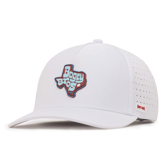 A white baseball cap with a perforated back panel, featuring a patch on the front in the shape of Texas with Bogey Bros written on it in bold lettering. Theres a small red tag on the side near the brim. The cap has a curved bill.