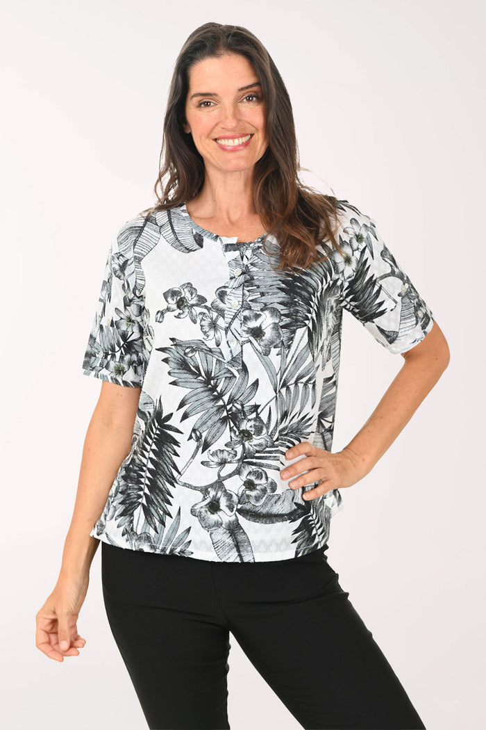 Woman wearing a black and white floral print top on a white background
