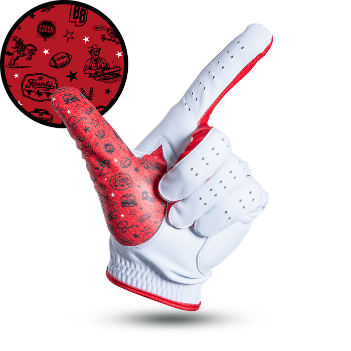 A white golf glove, palm up, points with index finger and thumb extended. The red palm features playful black cowboy-themed doodles. An inset shows these graphics in detail on a solid red background. Glove appears isolated on a white backdrop.