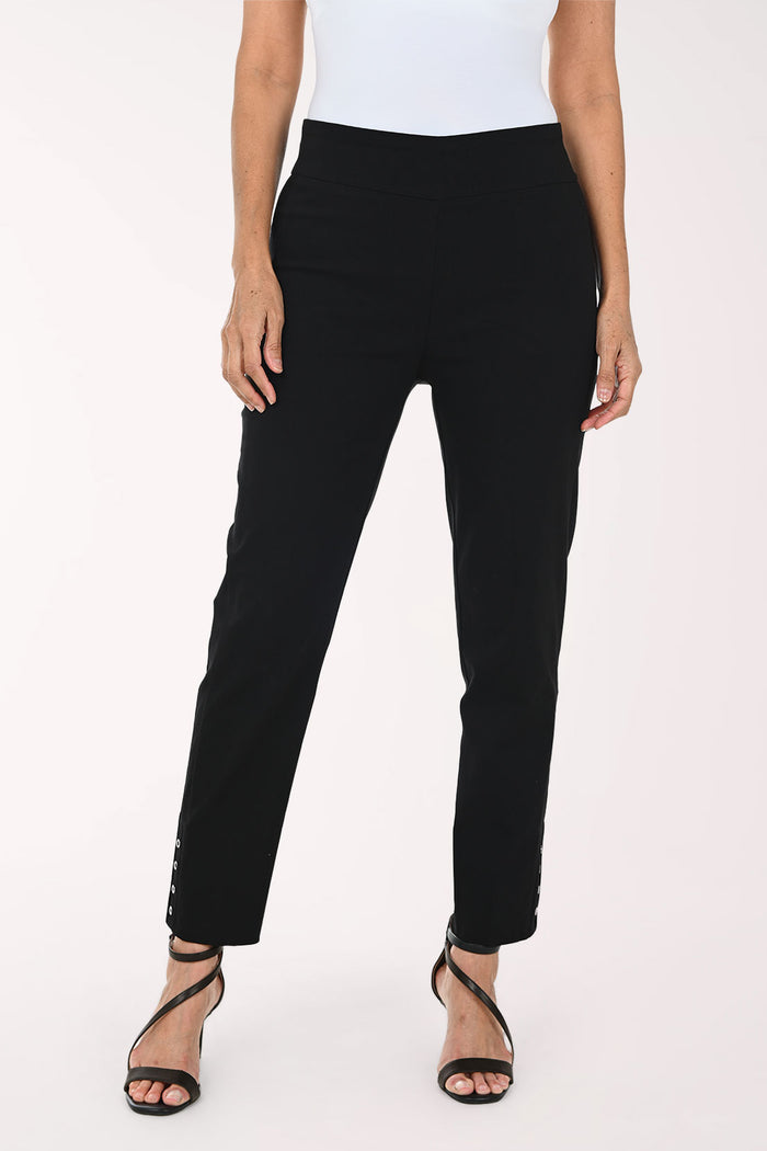 A model wearing black slim-fit ankle-length pants with decorative silver buttons on the lower hem, paired with a white top and black strappy heels, against a plain white studio background.