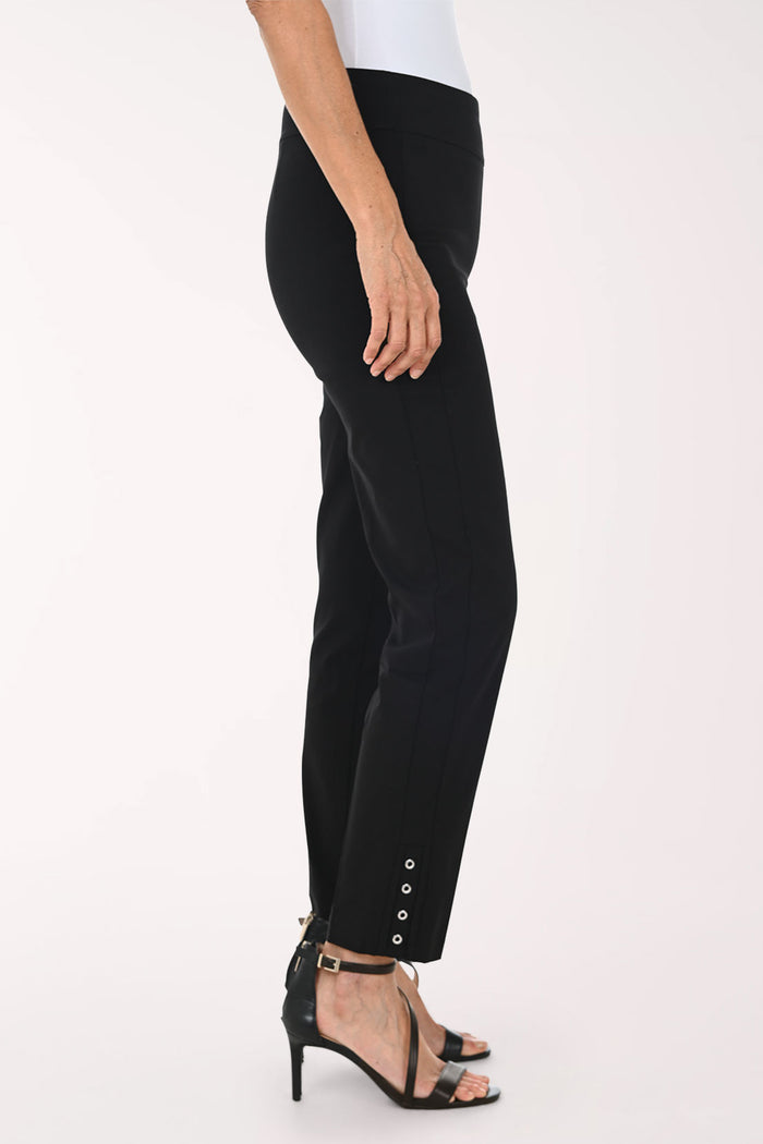 A model wearing black slim-fit ankle-length pants with decorative silver buttons on the lower hem, paired with a white top and black strappy heels, against a plain white studio background.