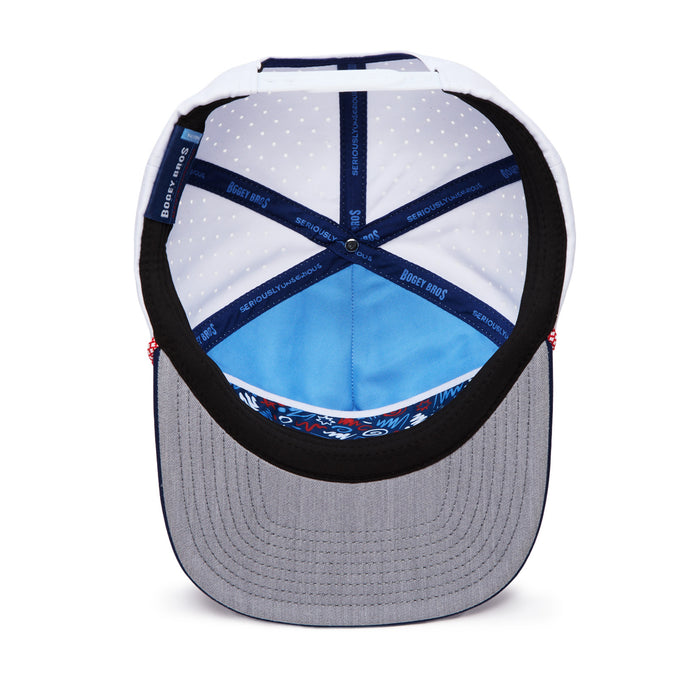A view of the inside of a baseball cap shows a gray brim, a blue inner lining with white polka dots, dark blue taping labeled “Bucket Bros,” and a colorful pattern at the inner front. Red stitching accents are visible on the sides.