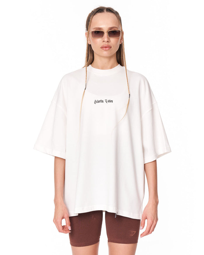 A woman modeling an oversized white t-shirt with 'Christian Dior' printed in black gothic font on the chest, paired with brown bike shorts and sunglasses, against a plain white background.