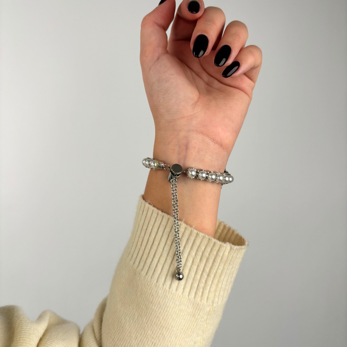 Hand with black nails wears a silver Coconut Lane Isla Pearl Apple Watch Strap, shown against a plain background.