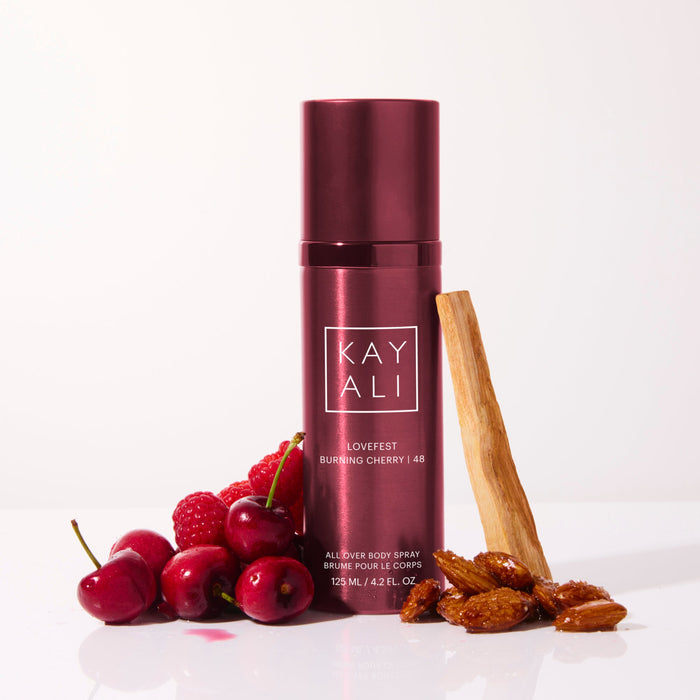 KAYALI body spray with cherries and almonds on a white background