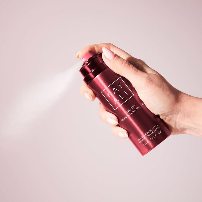 Hand holding a red bottle labeled 'KAYALI' against a light gray background