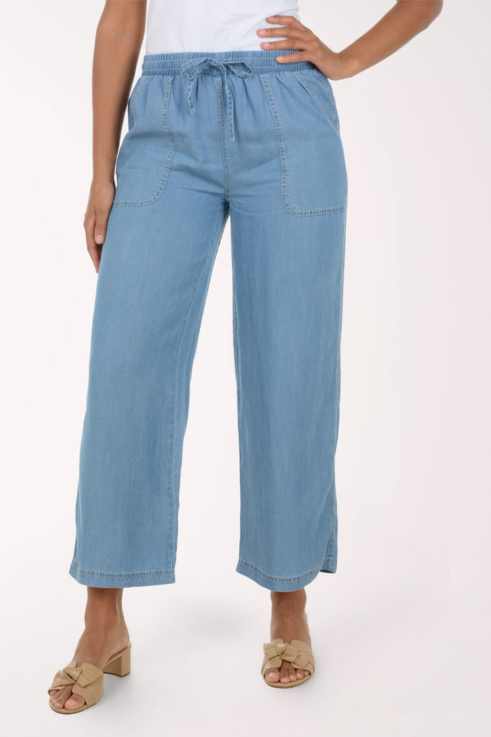 A model wearing light blue wide-leg cropped denim pants with a drawstring waist, paired with beige heeled sandals, against a plain light background.