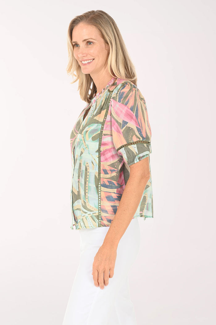 Woman wearing a colorful floral blouse against a white background