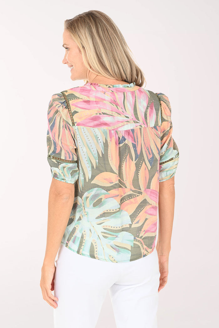 Woman wearing a colorful floral blouse against a white background