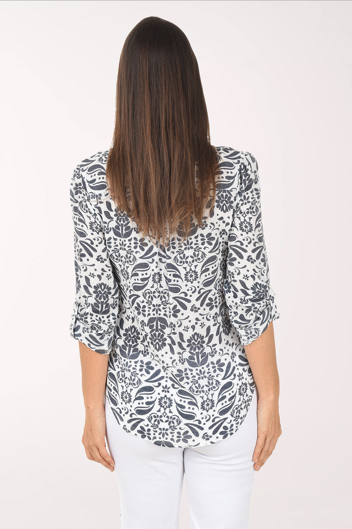Woman wearing a patterned blouse and white pants on a white background