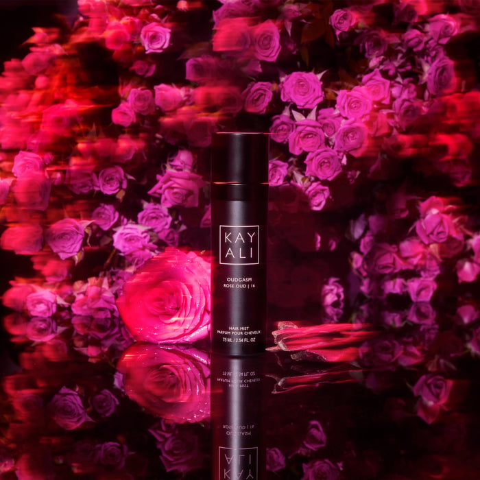 KAYALI product bottle surrounded by pink roses with a dark background