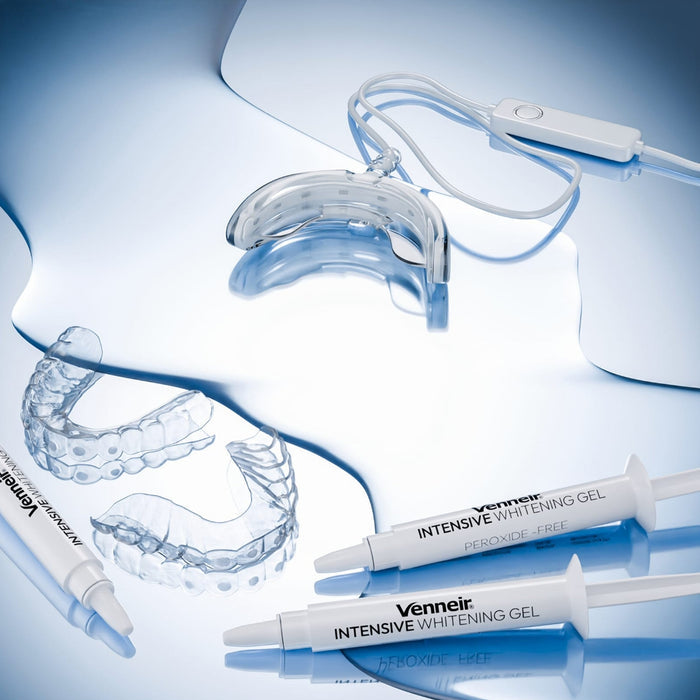 Flat-lay of teeth whitening kit with custom trays gel and LED light on blue background