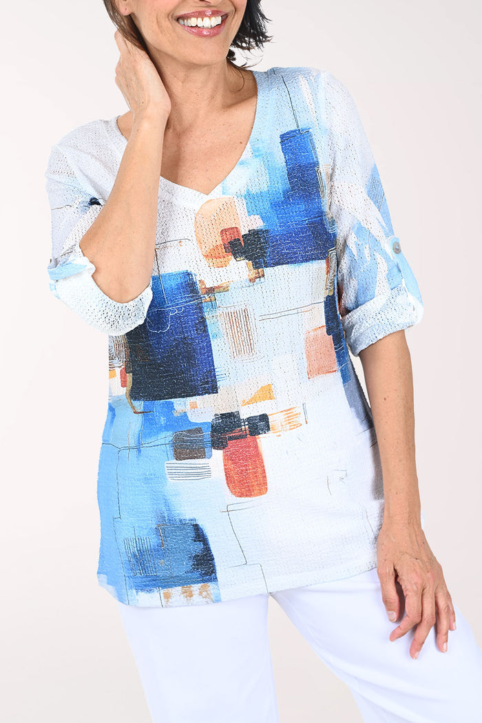 Woman wearing a colorful abstract patterned top against a plain background
