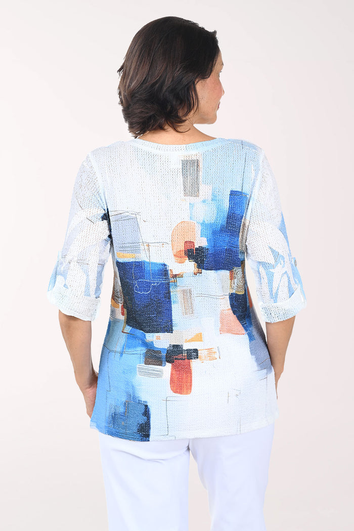 Woman wearing a colorful abstract patterned top against a plain background
