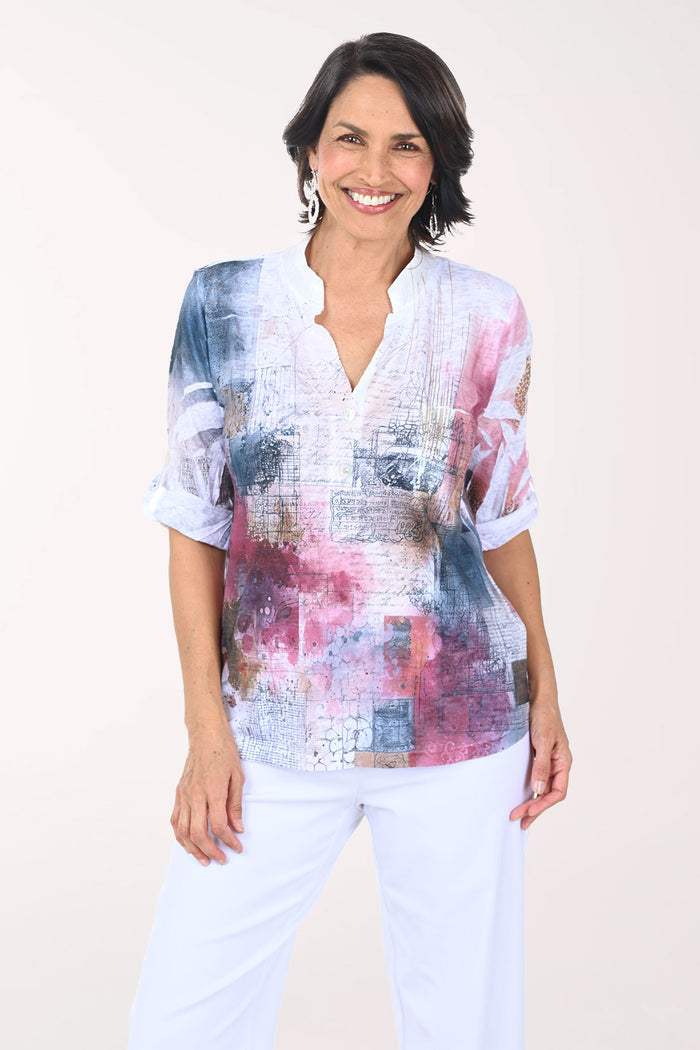 Woman wearing a colorful patterned blouse with a plain background