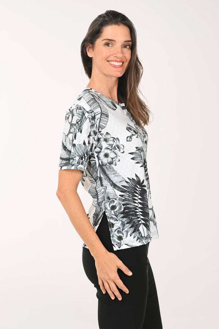 Woman wearing a black and white floral print top on a white background