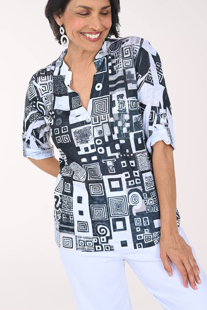 Woman wearing a black and white patterned blouse with a plain background