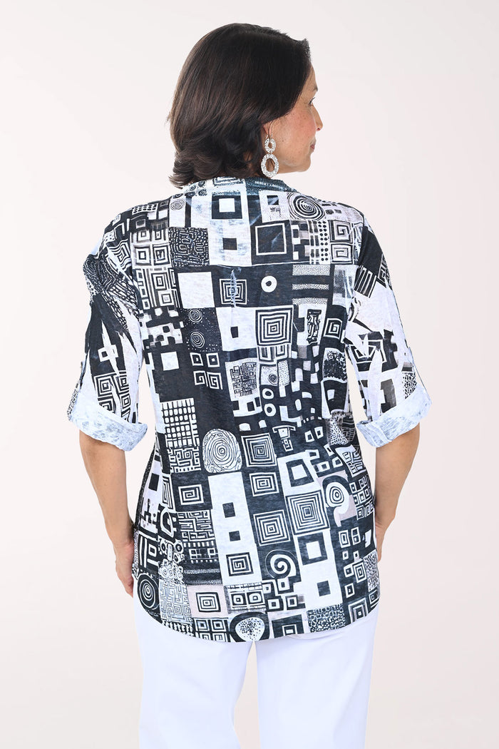 Woman wearing a black and white patterned blouse with a plain background