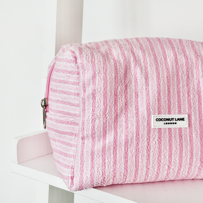 Powder Stripes towel makeup bag and matching scrunchie set in pastel stripes on a white shelf.